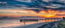 Sunset over ocean with pier in foreground