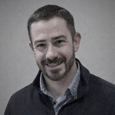 Headshot of man in button up and sweater