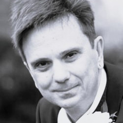 Black and white photo of person wearing collared shirt with boutonniere.