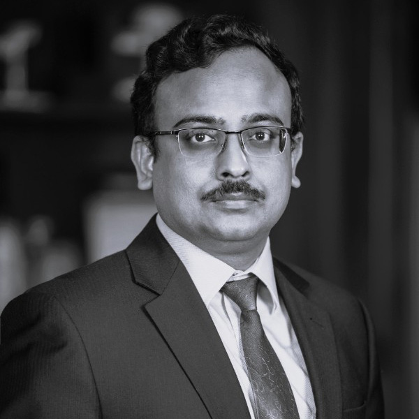 Black and white picture of person in suit and tie wearing glasses.
