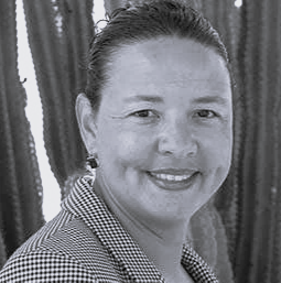 Black and white picture of person in blazer in front of cacti.
